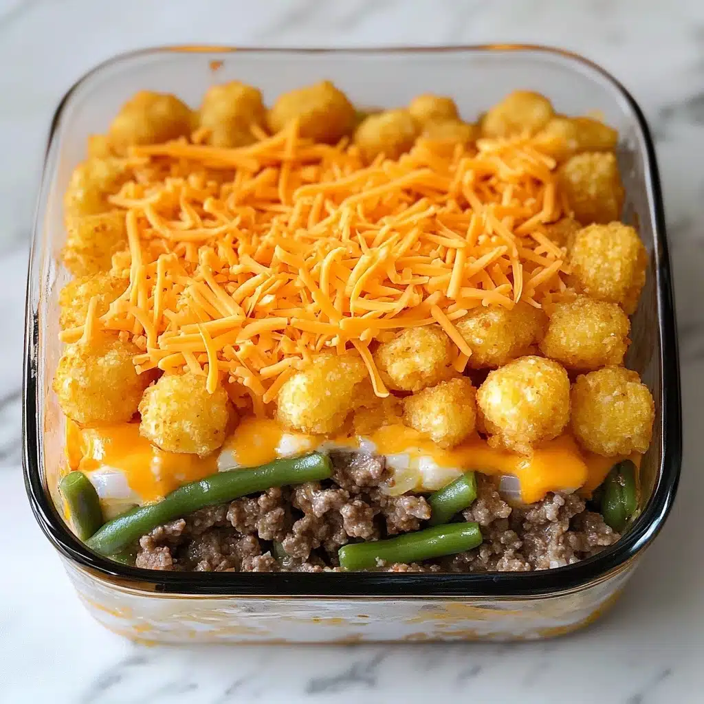 The BEST Tater Tot Casserole, delicious tater tot casserole, easy comfort food recipes, cheesy tater tot casserole, weeknight dinner ideas The image shows a clear glass baking dish filled with a layered casserole. The bottom layer appears to be green beans, followed by a smooth layer of melted orange cheese sauce. The top layer is covered with evenly spaced, golden-brown tater tots that have a crispy texture with some sprinkled coarse salt and black pepper visible. The baking dish rests on a white marbled surface.