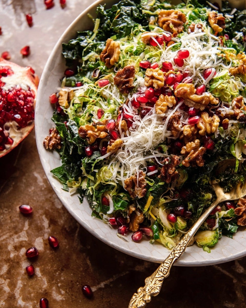 The image shows a close-up of a white shallow bowl filled with a colorful salad arranged in layers. The bottom layer is dark green shredded kale and lighter green shredded Brussels sprouts. Scattered on top are bright red pomegranate seeds and medium brown walnuts. Shredded white cheese is sprinkled over everything, adding texture and contrast. The salad looks fresh and vibrant with a mix of textures from crunchy nuts to soft cheese. A golden spoon with a carved handle rests in the bowl on the right side. The bowl sits on a brown surface with scattered pomegranate seeds around it, all set against a white marbled texture background. photo taken with an iphone --ar 4:5 --v 7