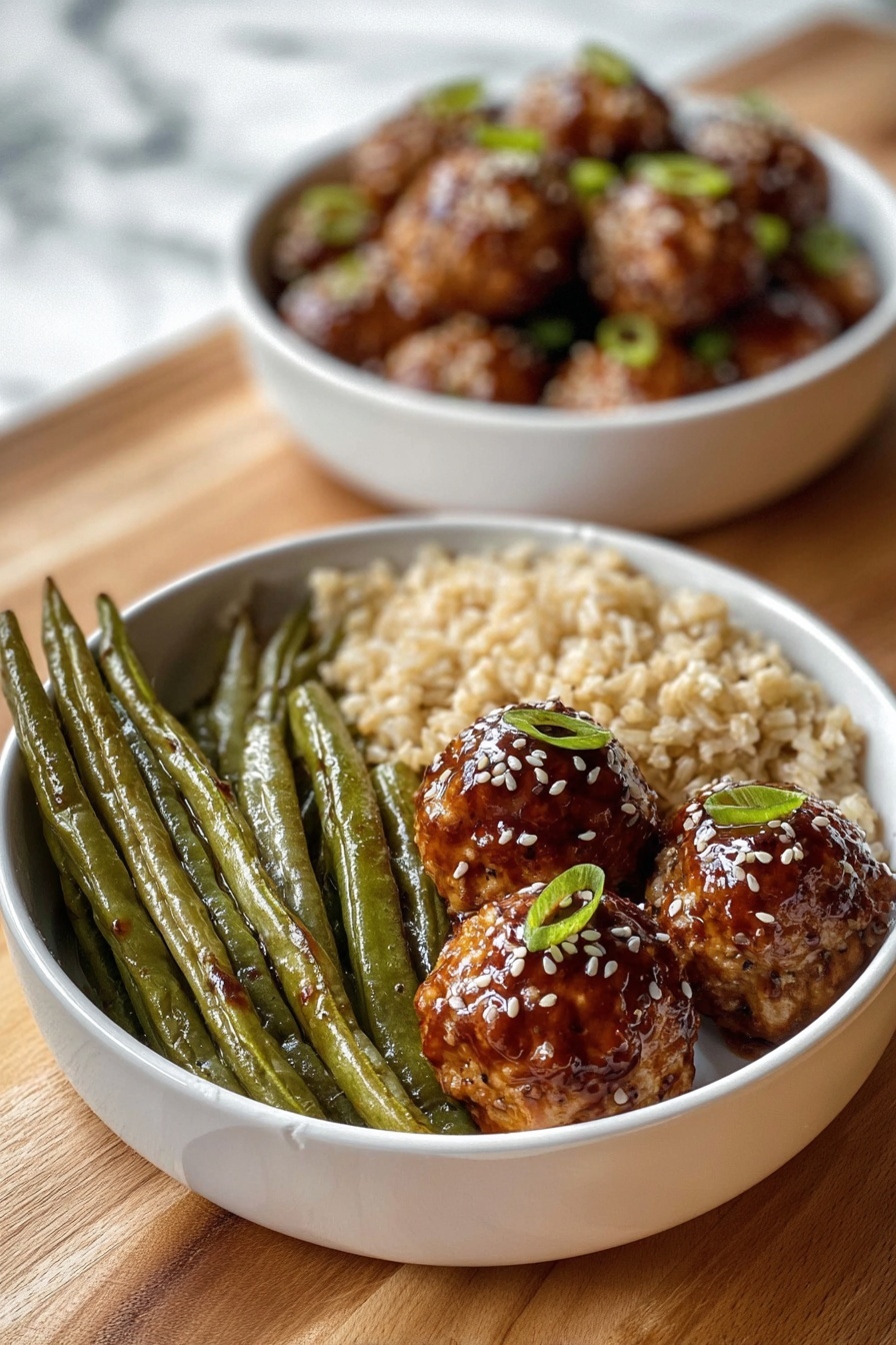 A white bowl contains three sections of food: on the left, a group of long, green roasted green beans with a slightly wrinkled texture; next to them at the bottom, a serving of light brown cooked rice with a soft, grainy look; on the right side, three round golden-brown meatballs covered with a shiny dark brown glaze, sprinkled with white sesame seeds and small green onion pieces on top. Behind this bowl, there is another white bowl filled with similar glazed meatballs, slightly blurred. Both bowls rest on a wooden surface with a white marbled texture background. Photo taken with an iphone --ar 2:3 --v 7 - Asian Glazed Turkey Meatballs, turkey meatballs recipe, Asian glazed meatballs, easy meatball recipes, flavorful turkey meatballs
