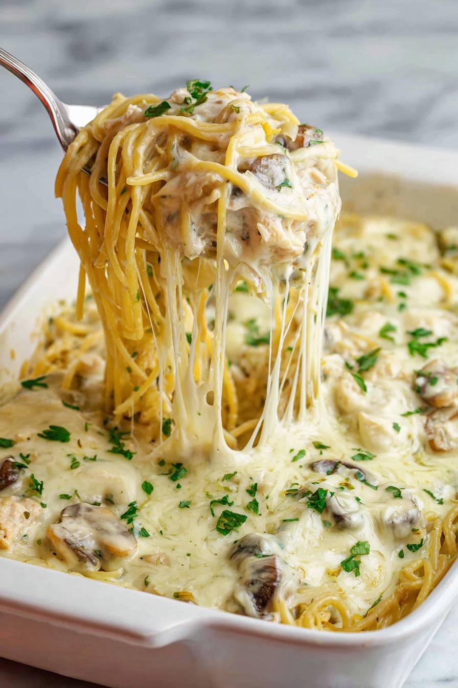 A white baking dish filled with creamy baked spaghetti is shown, featuring one thick layer of pasta mixed with mushrooms and shredded chicken, all covered with a smooth, melted white cheese sauce. The top layer is sprinkled with chopped fresh green herbs. A silver serving spoon lifts a portion of the spaghetti noodles, showing the soft texture and strands of melted cheese stretching from the dish. The background has a white marbled texture. Photo taken with an iphone --ar 2:3 --v 7 - Creamy Chicken Tetrazzini Bake, Chicken Tetrazzini casserole, cheesy pasta bake, cozy chicken pasta dish, easy creamy chicken bake