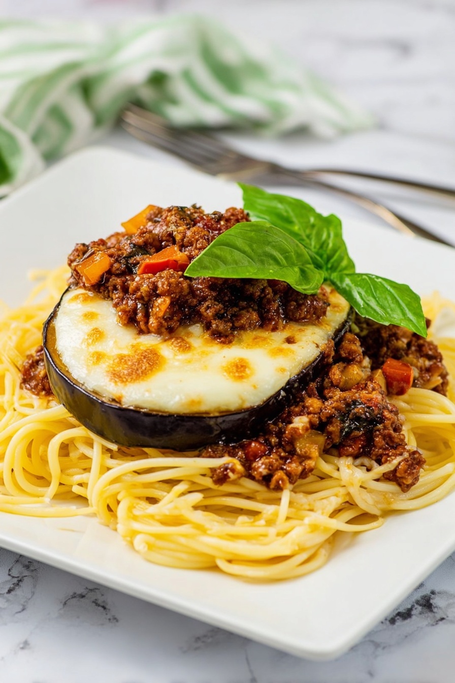 The dish shows a pile of yellow spaghetti noodles spread in a loose mound on a white square plate with rounded edges. On top of the noodles, there are slices of cooked eggplant with a glossy purple skin and soft interior, covered by a layer of melted, slightly browned white cheese. Between the eggplant layers, there are pieces of browned ground meat mixed with small bits of red tomatoes and mushrooms, adding texture and color. The top is garnished with fresh green basil leaves, adding a bright, leafy contrast. The plate sits on a white marbled surface with an orange and white striped cloth and a fork and knife placed behind it near the upper left edge. Photo taken with an iphone --ar 2:3 --v 7 - Eggplant Parmesan Spaghetti with Meat Sauce, Eggplant Parmesan pasta, Italian eggplant spaghetti, Meat sauce pasta with eggplant, cheesy eggplant spaghetti