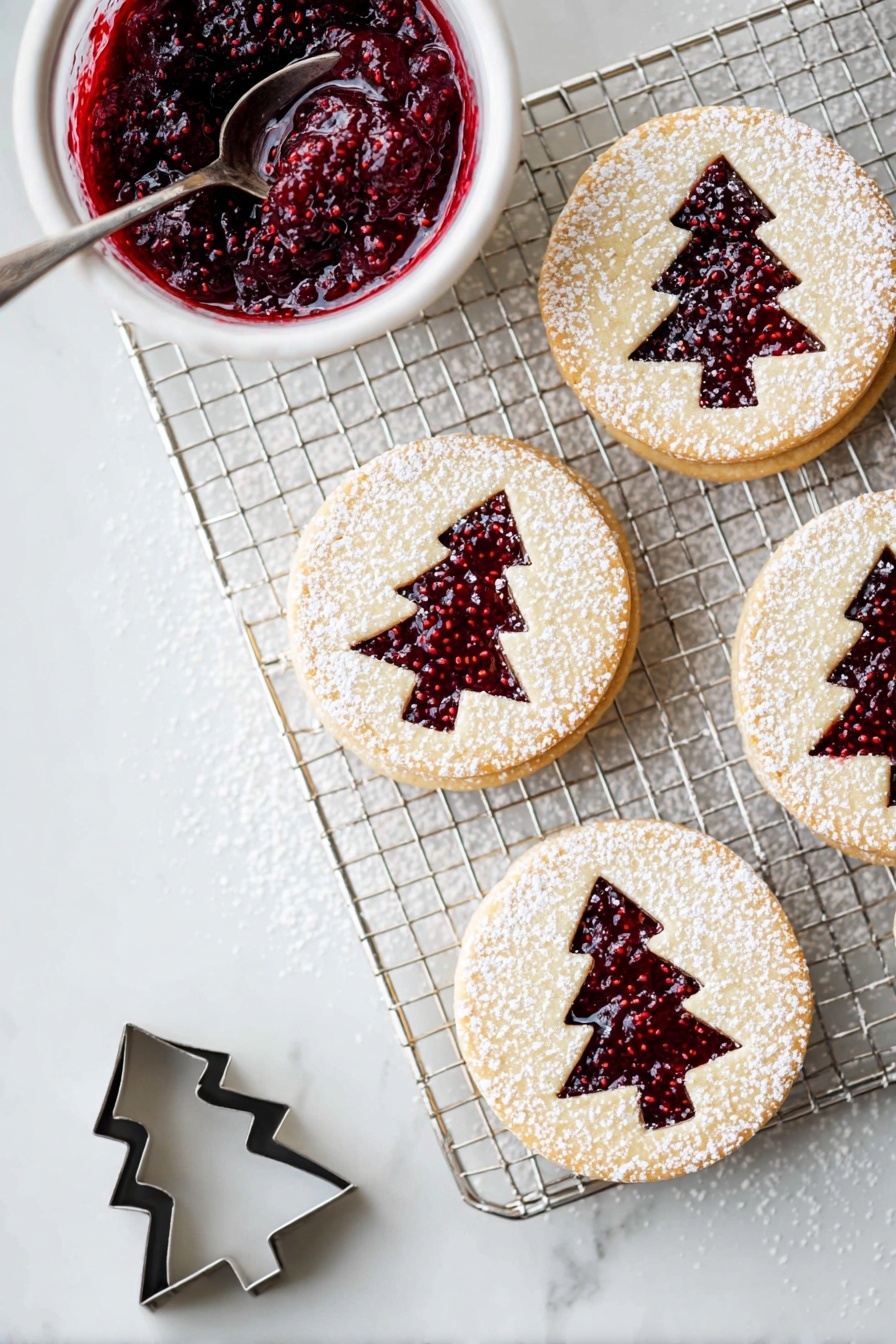 The image shows a cooling rack on a white marbled surface with four round layered cookies arranged on it and nearby. Each cookie has two layers: a light beige cookie base on the bottom, a layer of deep red raspberry jam in the middle, and a top cookie layer with a Christmas tree shape cut out, revealing the jam below. The top layer is dusted with white powdered sugar, creating a delicate snowy look. To the left of the rack is a small white bowl filled with thick, dark red raspberry jam with visible seeds, and a silver spoon inside. Near the bottom left corner, there is a small metal cookie cutter in the shape of a Christmas tree. photo taken with an iphone --ar 2:3 --v 7 - Raspberry Linzer Cookies, shortbread jam cookies, easy raspberry cookies, homemade Linzer cookies, tart raspberry pastry treats