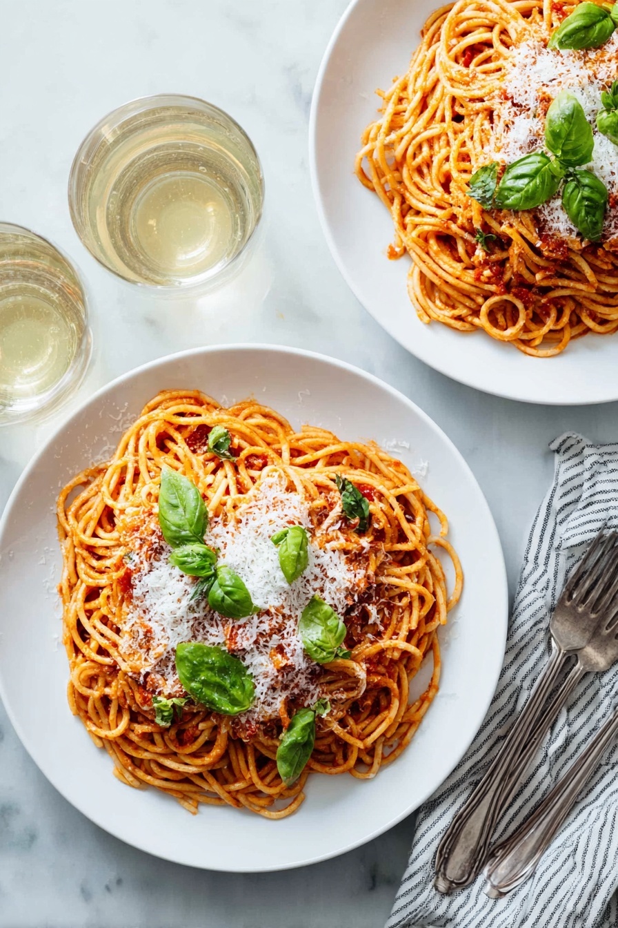 Two white plates with round shapes, each holding a serving of spaghetti layered with red tomato sauce, topped with a layer of white grated cheese and scattered green basil leaves. The spaghetti is twisted into small nests that fill most of the plate. Near the plates are two forks resting on a white and blue striped cloth napkin, and two almost full glasses of white wine are seen in the top left corner. Everything is set on a white marbled table surface. photo taken with an iphone --ar 2:3 --v 7 - Simple Pasta Pomodoro, pasta pomodoro, Italian pasta recipe, quick tomato pasta, easy Italian dinner