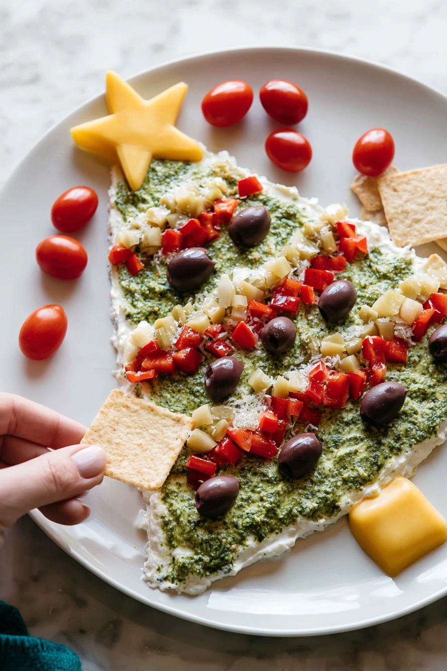 The image shows a white plate with a Christmas tree-shaped layered dip. The first layer is a smooth, white creamy base covering the entire tree shape. The second layer is a rough, green spread resembling pesto, filling most of the tree shape except the edges. On top, there are several red diced pepper pieces forming three diagonal lines across the tree. Small dark purple olive slices are scattered evenly over the green layer. There are small chunks of pale yellow artichoke hearts mixed in with the red peppers. Bright red cherry tomatoes decorate the edges, with a large yellow star-shaped piece placed at the top of the tree. A woman's hand is holding a square chip near the plate on a white marbled surface photo taken with an iphone --ar 2:3 --v 7 - Christmas Tree Bean Dip with Pesto, festive holiday appetizer, easy Christmas dip recipes, vegetarian holiday snacks, party dips for Christmas