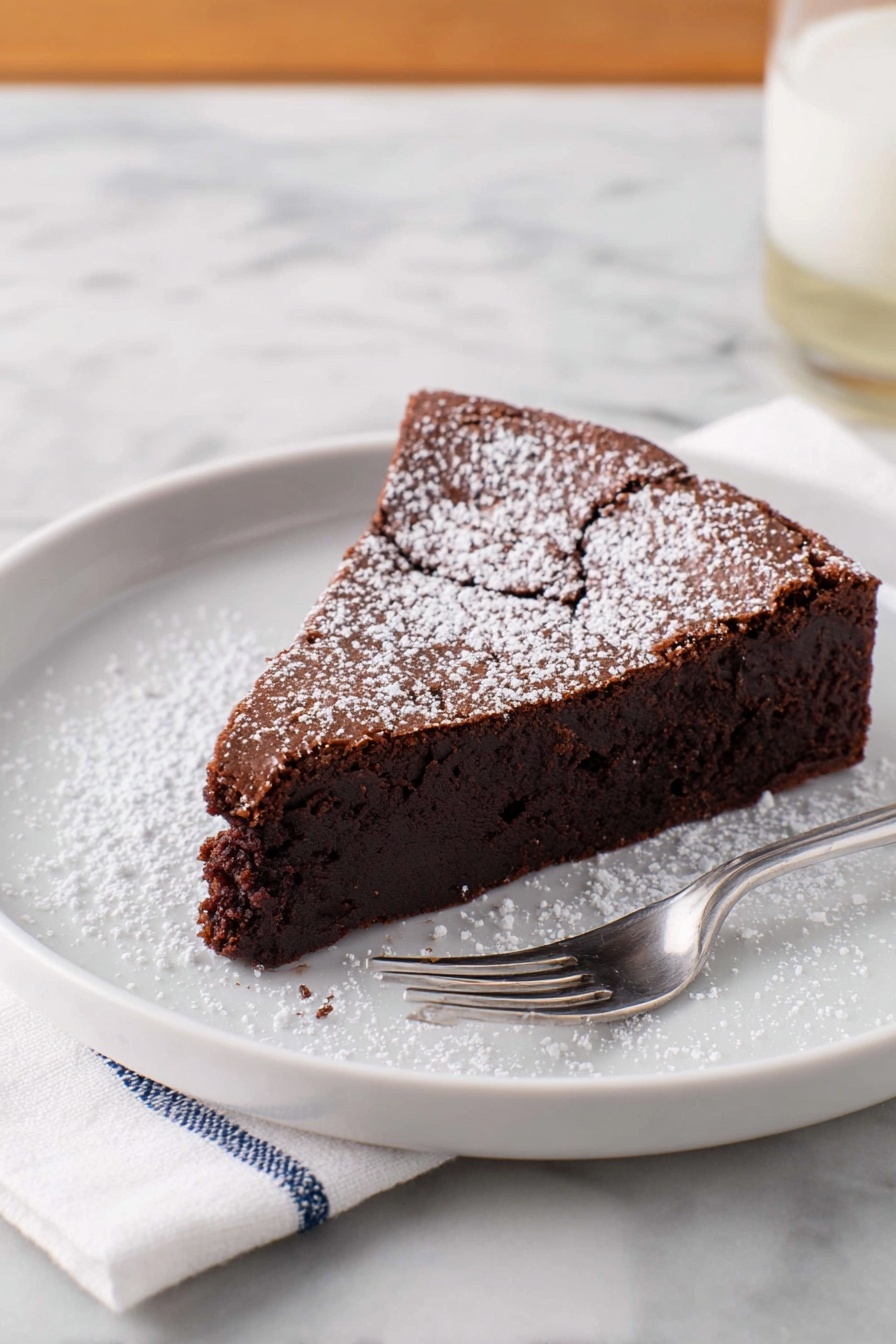 A single slice of dark brown chocolate cake with a slightly cracked top layer is placed on a white plate. The cake has one thick layer that looks moist and dense, dusted with a light sprinkle of white powdered sugar on top and around the plate. A silver fork rests on the plate next to the cake. The plate sits on a white marbled surface with a white napkin with blue stitching beside it. Photo taken with an iphone --ar 2:3 --v 7 - Flourless Chocolate Torte, gluten-free chocolate dessert, decadent chocolate torte, easy chocolate cake, rich flourless chocolate cake
