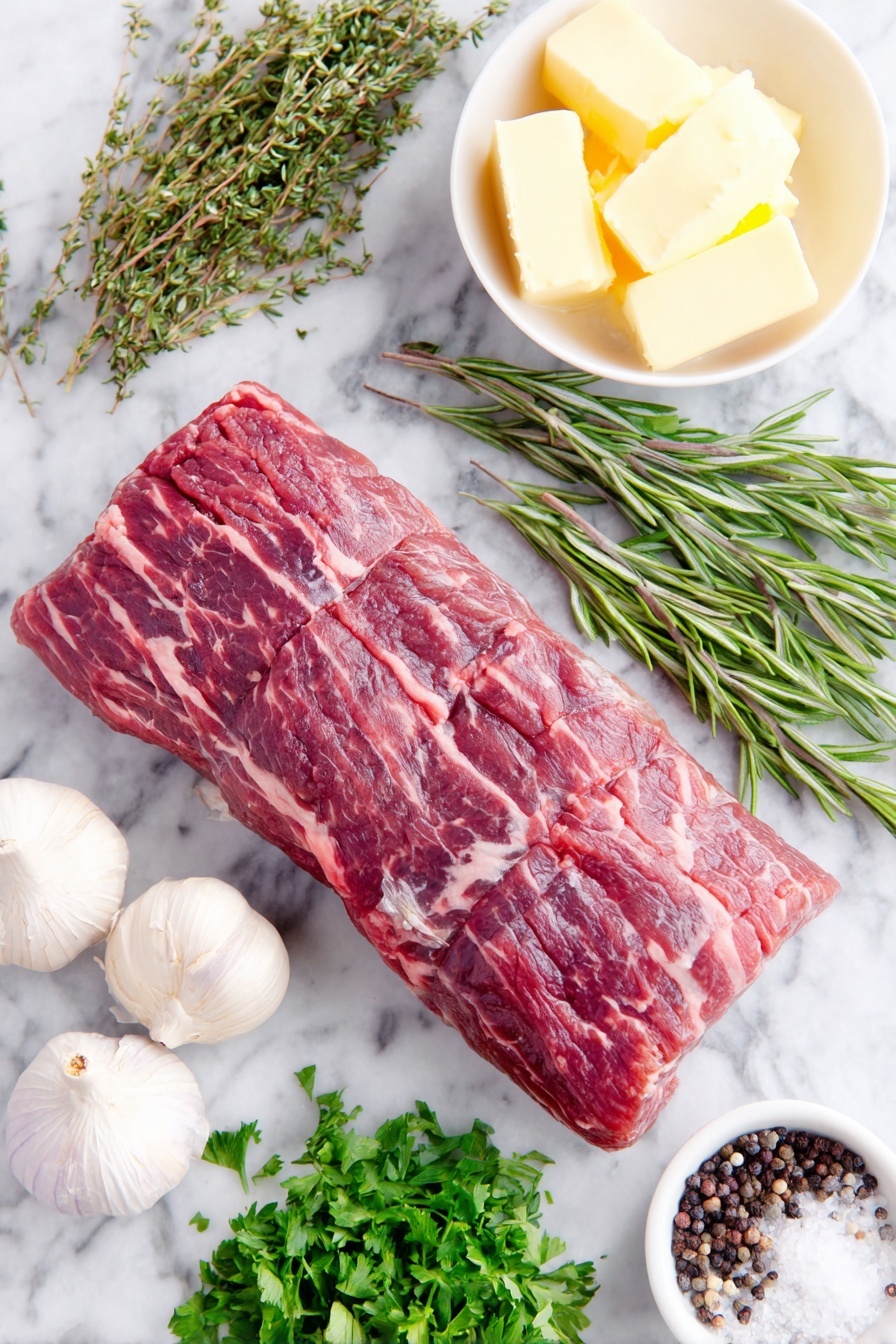 Flat lay of a whole trimmed beef tenderloin roast with a rich red color and fine marbling, three whole uncracked garlic cloves with smooth white skins, a small heap of fresh flat-leaf parsley sprigs, fresh rosemary sprigs with needle-like leaves, fresh oregano sprigs with small green leaves, a few whole black peppercorns scattered naturally, a small white ceramic bowl holding softened pale yellow butter, a small white bowl with dark glossy balsamic vinegar, a small white bowl of thick Worcestershire sauce with a deep brown hue, and a small pile of coarse sea salt crystals, all arranged symmetrically with perfect balance, placed on a clean white marble surface, soft natural light, photo taken with an iPhone, professional food photography style, fresh ingredients, white ceramic bowls, no bottles, no duplicates, no utensils, no packaging --ar 2:3 --v 7 --p m7354615311229779997 - Oven-Roasted Beef Tenderloin with Garlic Butter, Roast Beef Tenderloin, Garlic Butter Beef, Elegant Roast Beef Recipe, Juicy Beef Tenderloin