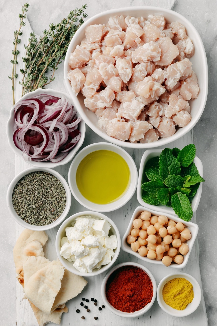 Flat lay of a small pile of ground chicken, a halved and finely diced yellow onion, a few sprigs of dried oregano and thyme arranged neatly, a scattering of whole black peppercorns, a few whole bright yellow turmeric roots next to a small pile of paprika powder and garlic powder, a small white ceramic bowl of extra-virgin olive oil, a small white ceramic bowl with crumbled fresh feta cheese, a handful of fresh flat-leaf parsley and mint leaves, four halved and sliced Persian cucumbers, a small white ceramic bowl filled with pickled red onions, a small white ceramic bowl with roasted chickpeas, a portion of cooked jasmine rice shaped tidily, and a few torn pieces of warm pita bread, all placed on a clean white marble surface, soft natural light, photo taken with an iPhone, professional food photography style, fresh ingredients, white ceramic bowls, no bottles, no duplicates, no utensils, no packaging --ar 2:3 --v 7 --p m7354615311229779997 - Mediterranean Spiced Chicken Bowls, Mediterranean chicken dinner, flavorful chicken rice bowls, easy Mediterranean dinner, healthy chicken bowl recipes
