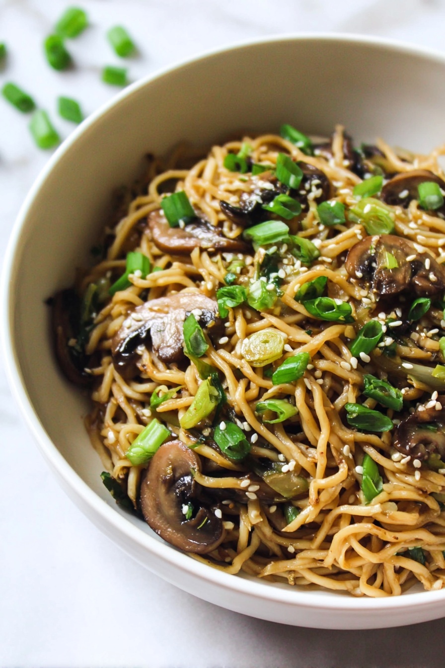 The image shows one white bowl filled with cooked noodles mixed with sliced brown mushrooms and chopped green onions. The noodles are light brown and slightly glossy, while the mushrooms are darker brown with a soft texture. The green onion pieces are vibrant green, scattered on top along with small white sesame seeds. The bowl is placed on a white marbled surface, creating a clean and bright background. Photo taken with an iphone --ar 2:3 --v 7 - Mushroom Ramen Noodles, easy ramen recipes, vegan ramen bowl, quick weeknight dinners, flavorful mushroom ramen