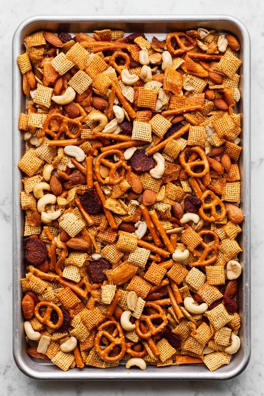 A large white baking tray filled with a mixed snack party food laid out evenly. The mix has small square cereal pieces in light brown, round dark reddish-brown slices, small orange pretzels, light orange stick-shaped crackers, off-white cashew nuts, and a few whole almonds scattered on top. All pieces have a crunchy texture, and the tray rests on a white marbled surface. Photo taken with an iphone --ar 2:3 --v 7 - Sweet and Spicy Chex Mix, Chex Mix snacks, easy party snacks, crunchy spicy snack, honey cayenne trail mix