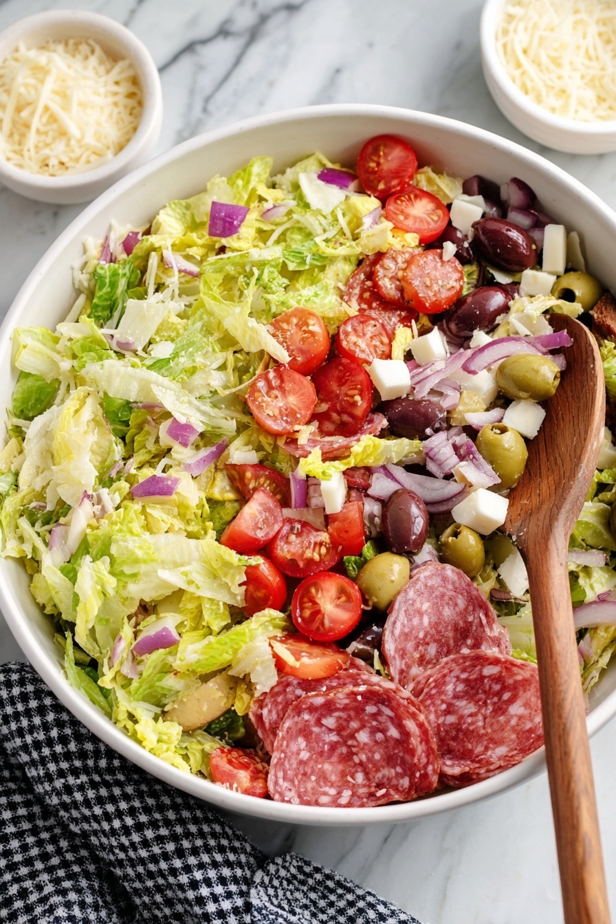 A large white bowl filled with a colorful mixed salad showing three main layers: at the bottom, light green shredded lettuce with a fresh, crisp texture; scattered through the middle, shiny slices of pinkish-red salami, small white cheese cubes, and pale yellow pepper strips; on top, bright red cherry tomato halves, thin purple onion slices, dark purple Kalamata olives, and white cheese shavings. A wooden spoon rests inside the bowl on the right side, slightly lifting some salad. The bowl is set on a white marbled surface with a small white bowl of cheese shavings behind it and a black and white checkered cloth nearby. Photo taken with an iphone --ar 2:3 --v 7 - Italian Brussels Sprouts Salad, Brussels Sprouts Salad with Italian Dressing, Easy Brussels Sprouts Salad, Healthy Brussels Sprouts Side Dish, Vegetarian Brussels Sprouts Salad