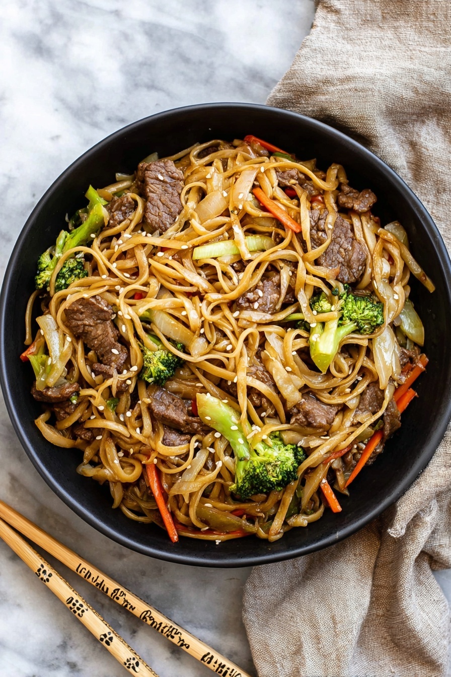 A black bowl filled with stir-fried noodles mixed with pieces of beef, bright green broccoli florets, thin orange carrot strips, and light brown cooked onions, all coated in a light sauce giving a slight shine; the noodles are long and a pale tan color, twisting through the vegetables and meat, garnished with small white sesame seeds. The bowl sits on a white marbled surface next to a pair of light wooden chopsticks decorated with simple patterns, and a beige cloth napkin is casually placed nearby. photo taken with an iphone --ar 2:3 --v 7 - Easy Beef Lo Mein, Beef Lo Mein stir-fry, homemade lo mein, quick Asian noodles, beef noodle skillet