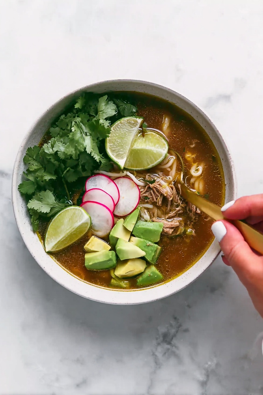 A white bowl filled with soup that has a brownish broth at the bottom layer mixed with pieces of shredded meat and small white noodles. On top of the soup, there are bright green chunks of avocado stacked on one side and thin slices of radish with a pale pink color beside them. Fresh green cilantro leaves are also scattered over the soup. A gold spoon is placed inside the bowl, partially submerged in the broth. Above the bowl, a woman's hand holding a lime wedge is about to squeeze it into the soup. The surface beneath the bowl is a white marbled texture. photo taken with an iphone --ar 2:3 --v 7 - Slow Cooker Chicken Posole Verde, Chicken Posole Verde, Green Chicken Posole, Posole Verde recipe, Mexican chicken stew
