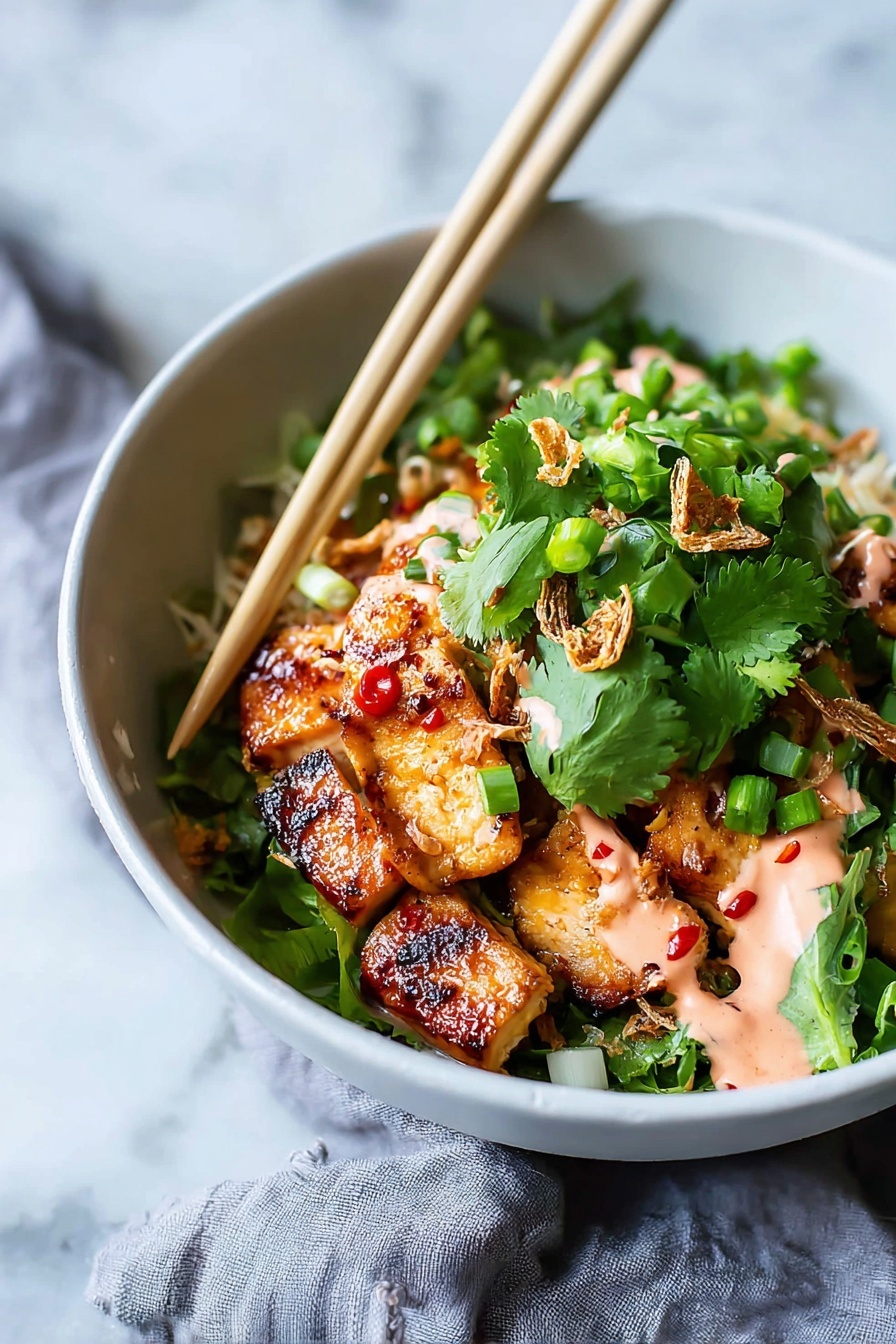A white bowl holds a colorful dish with several layers starting with golden-brown grilled chicken pieces that have a shiny glaze with small red chili spots, placed at the bottom. On top there is a generous layer of fresh, bright green cilantro leaves and chopped green onions, adding a fresh texture. Some crispy fried shallots are scattered over the greens, and drizzled in spots is a light pink creamy sauce. A pair of light wood chopsticks rest on the rim of the bowl, angled over the food. The bowl sits on a white marbled surface with a soft gray cloth partly visible beside it. Photo taken with an iphone --ar 2:3 --v 7 - Sticky Glazed Tofu Bowls with Yum Yum Sauce, plant-based tofu bowls, healthy tofu bowl recipes, easy tofu dinner ideas, flavorful Asian tofu dishes