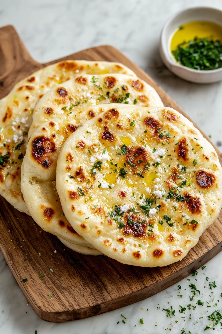 Four flat round breads with golden brown spots lay stacked on a wooden board, each topped with melted butter and small bits of white cheese sprinkled with chopped green herbs. The wooden board sits on a white marbled surface, with a small bowl of oil and some scattered herbs nearby. photo taken with an iphone --ar 2:3 --v 7 - Cottage Cheese Flatbreads, quick flatbread recipe, easy bread recipes, healthy flatbreads, a delicious flatbread idea