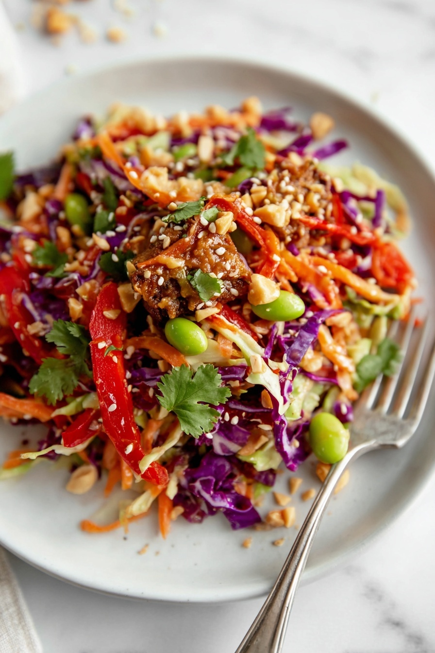 A close-up of a white plate with a colorful salad featuring shredded purple and light green cabbage as the bottom layer. On top, there are bright orange carrot strips and red bell pepper slices mixed with green edamame beans and pieces of brown tempeh. The salad is sprinkled with white sesame seeds, crushed peanuts, and small green cilantro leaves. The texture looks fresh and crunchy, with a fork resting on the right side of the plate, against a white marbled background. photo taken with an iphone --ar 2:3 --v 7 - Asian Chicken Crunch Salad, Asian Chicken Salad, Crunchy Asian Salad, Healthy Chicken Salad, Asian Dinner Ideas