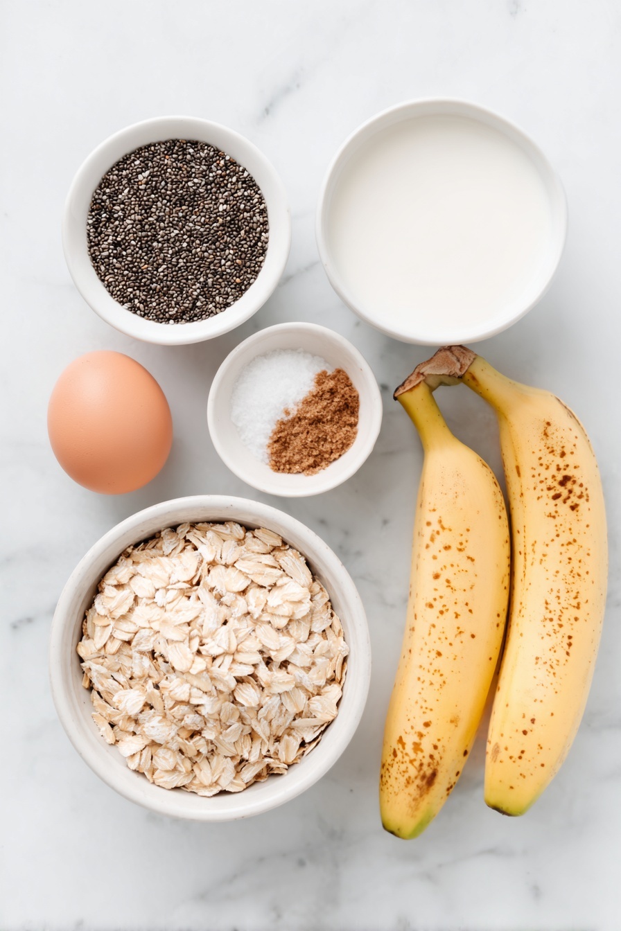 Flat lay of rolled oats in a small pile, a small white ceramic bowl filled with black chia seeds, a small white bowl with dark brown sugar crystals, two ripe bananas whole with natural spots, a small white bowl of ground cinnamon powder, one whole uncracked brown egg (to represent vanilla extract as no vanilla bean is visible), a small white bowl with fine salt crystals, and a simple white ceramic bowl filled with fresh milk, all arranged symmetrically and balanced, placed on a clean white marble surface, soft natural light, photo taken with an iPhone, professional food photography style, fresh ingredients, white ceramic bowls, no bottles, no duplicates, no utensils, no packaging --ar 2:3 --v 7 --p m7354615311229779997 - Brown Sugar Overnight Oats, healthy overnight oats, easy breakfast recipes, sweet breakfast ideas, protein-packed overnight oats