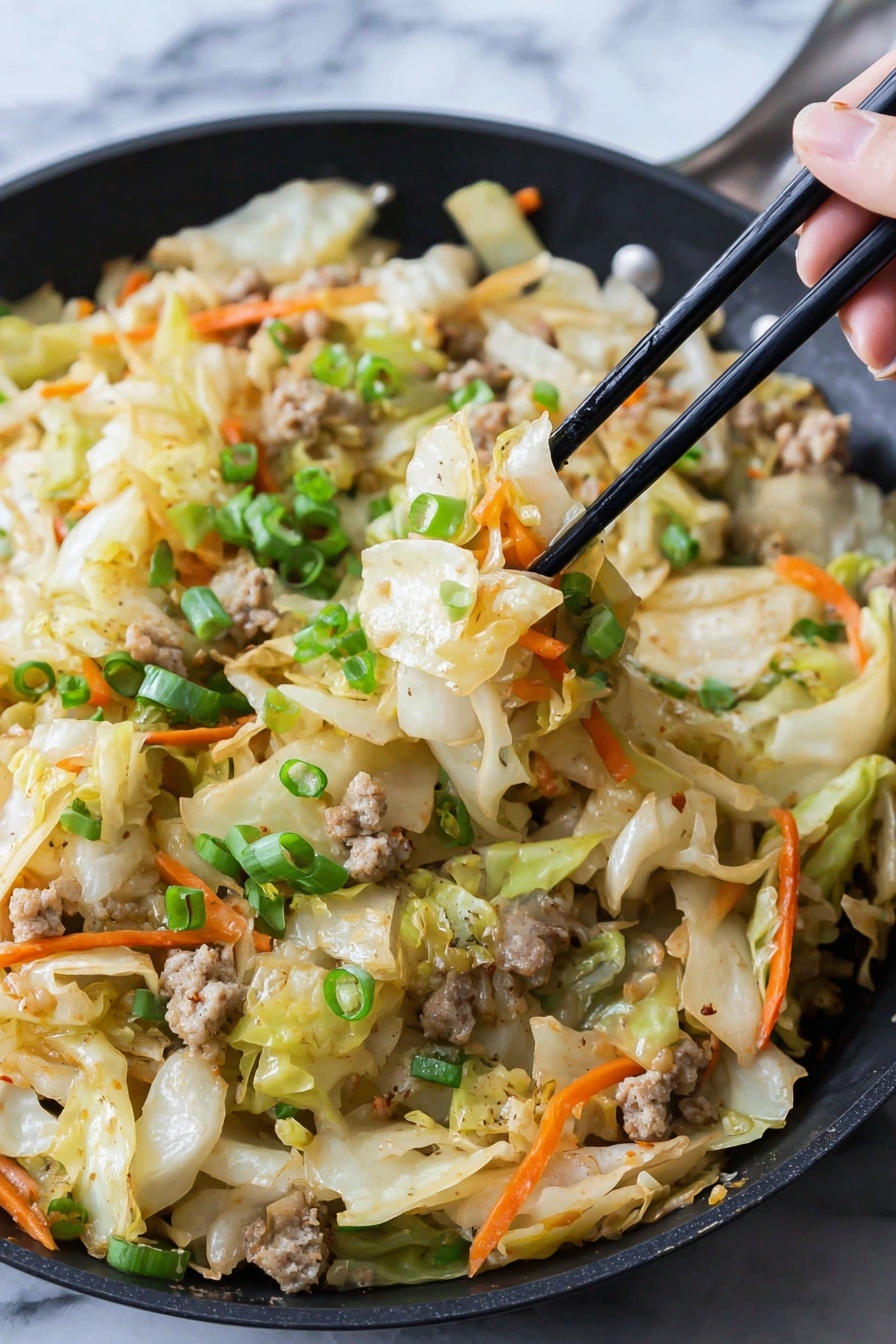 In a black pan, there is a mix of cooked cabbage pieces that are pale yellow with a soft texture, thin orange carrot strips scattered throughout, and small light brown cooked meat bits. On top, bright green chopped scallions add freshness. A woman's hand holds black chopsticks lifting a portion showing these layers clearly. The food looks slightly shiny as if lightly cooked with seasoning. The background surface is white marbled texture. photo taken with an iphone --ar 2:3 --v 7 - Egg Roll in a Bowl, easy egg roll stir-fry, healthy egg roll bowl, quick weeknight dinner ideas, low carb Asian recipes