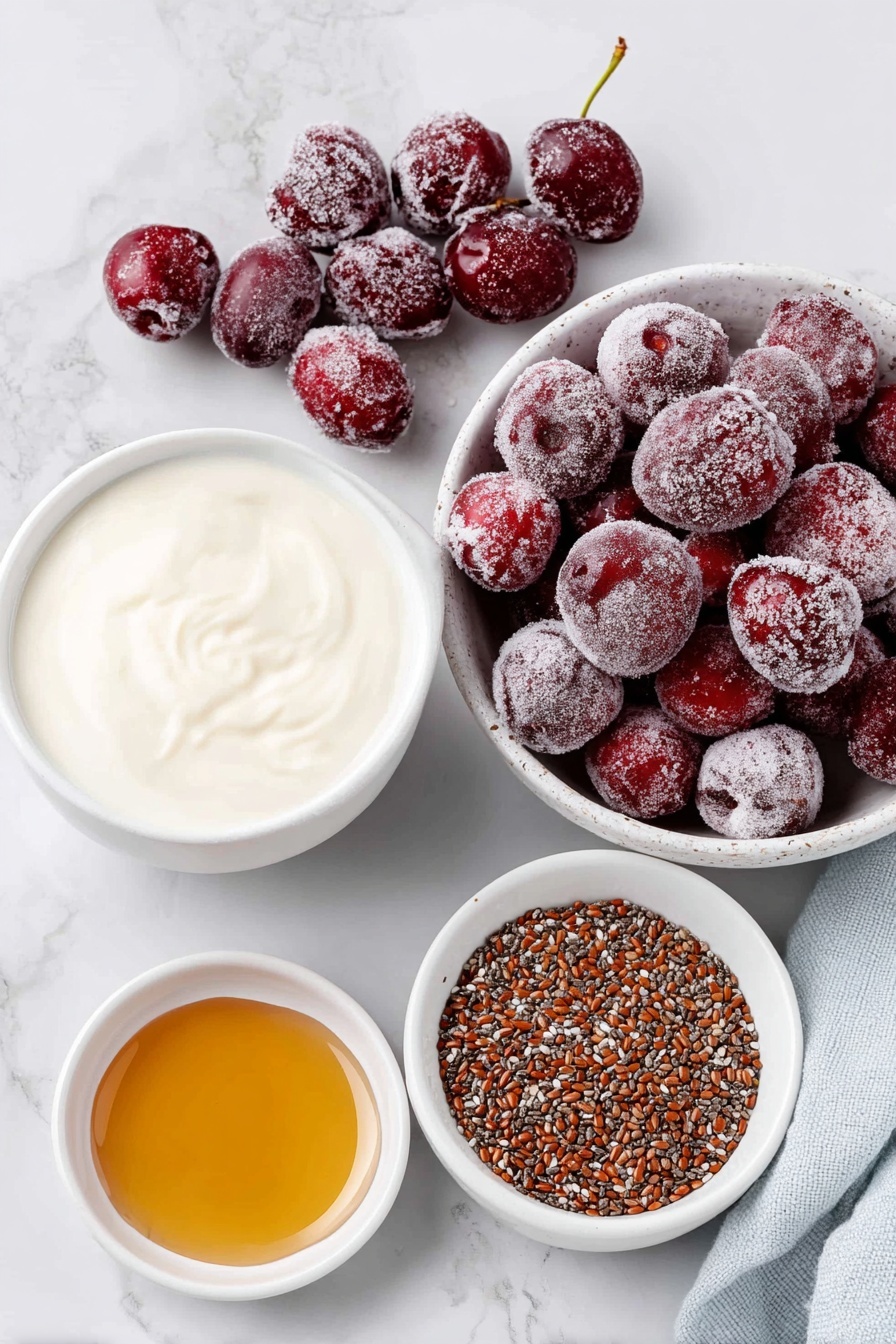 Flat lay of a small pile of bright frozen cherries with frost, a small mound of whole chia seeds, a small white ceramic bowl filled with creamy dairy-free milk, a small white bowl holding amber maple syrup, and a small white bowl containing clear almond extract liquid, all arranged symmetrically on a clean white marble surface, soft natural light, photo taken with an iPhone, professional food photography style, fresh ingredients, white ceramic bowls, no bottles, no duplicates, no utensils, no packaging --ar 2:3 --v 7 --p m7354615311229779997 - Cherry Chia Pudding, healthy chia seed pudding with cherries, easy cherry chia pudding, nutritious fruit chia pudding, quick breakfast cherry pudding